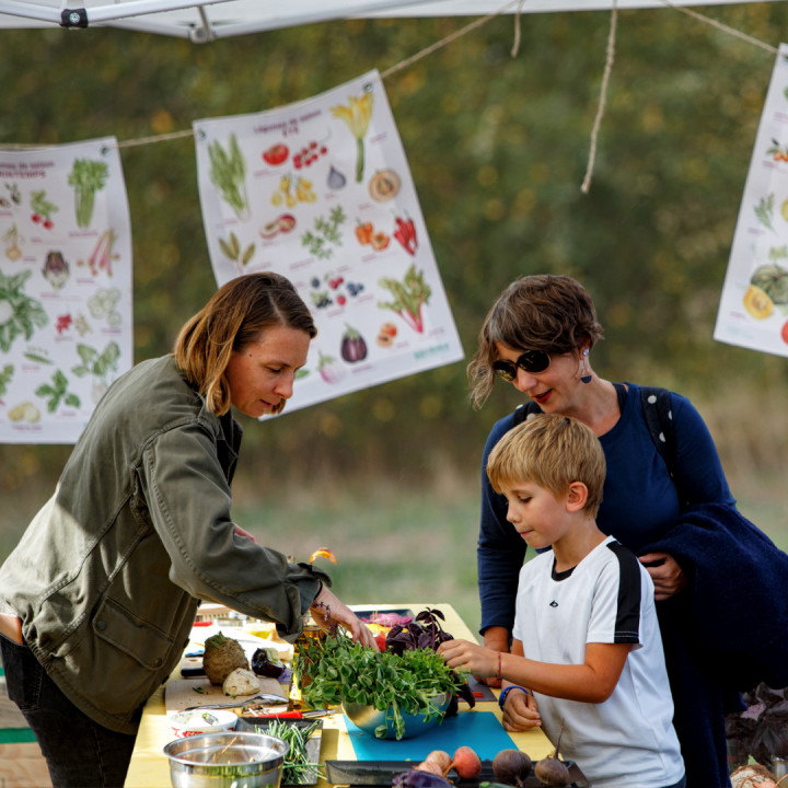 Enseignante et enfant autour de légumes à l'extérieur